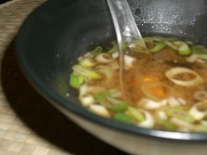 Bol en céramique asiatique noire contenant une portion de soupe  miso